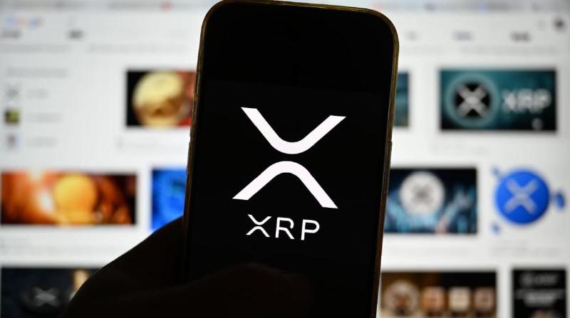 Een afbeelding van het logo van cryptomunt XRP op een mobiele telefoon met op de achtergrond veel content van de munt