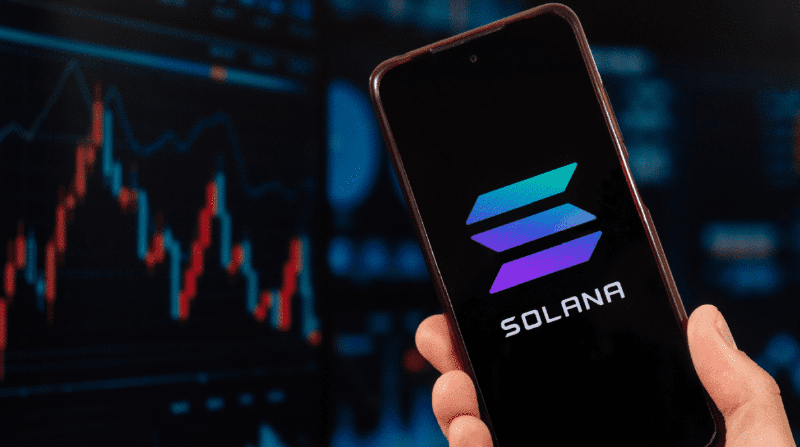 Logo Solana di ponsel dengan grafik harga yang menurun
