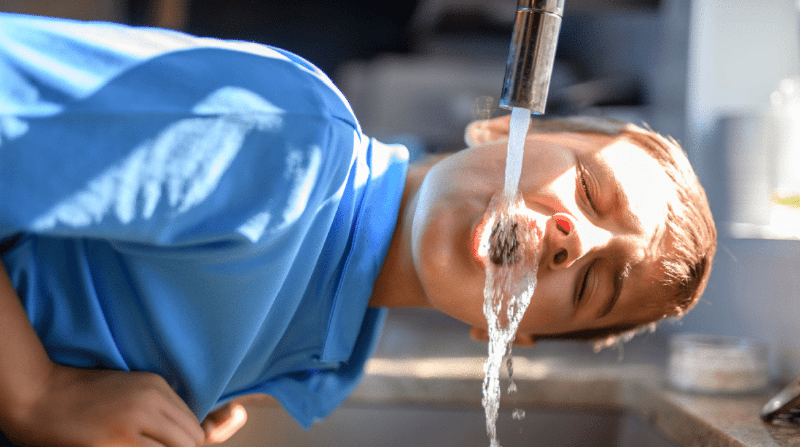 Anak laki-laki menekan air dari keran