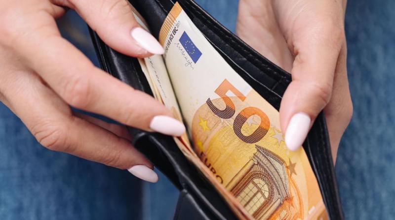 Seorang orang membuka dompet untuk mengambil uang kertas Euro